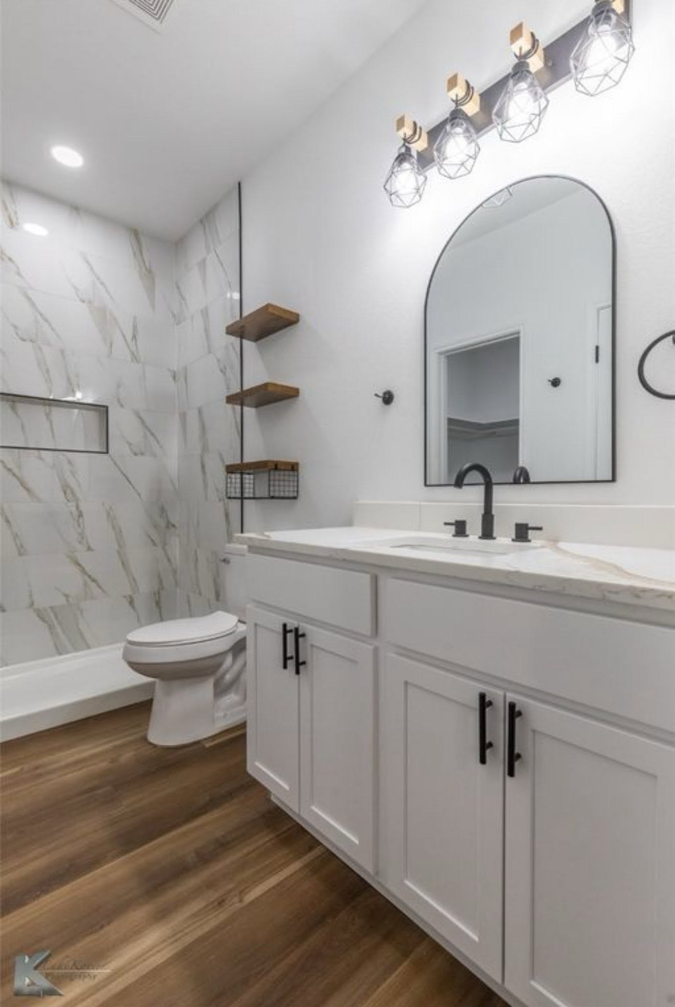 Finished bathroom with white vanity, tiled shower, and dark fixtures