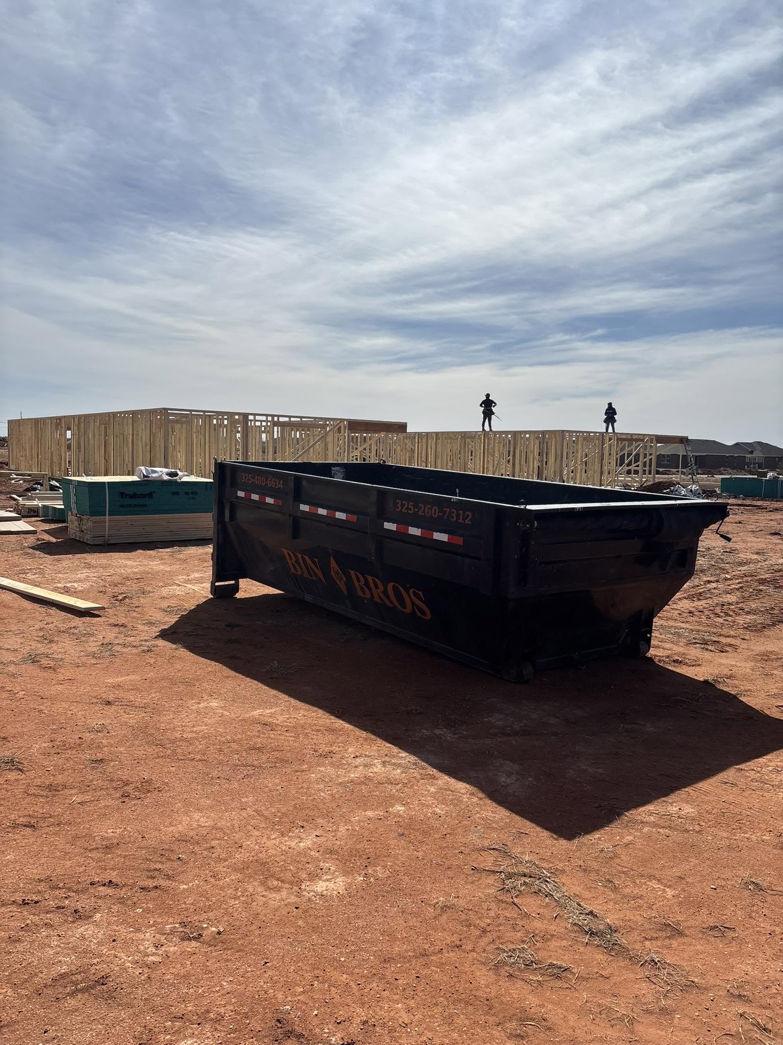 Bin Bros dumpster beside active home framing