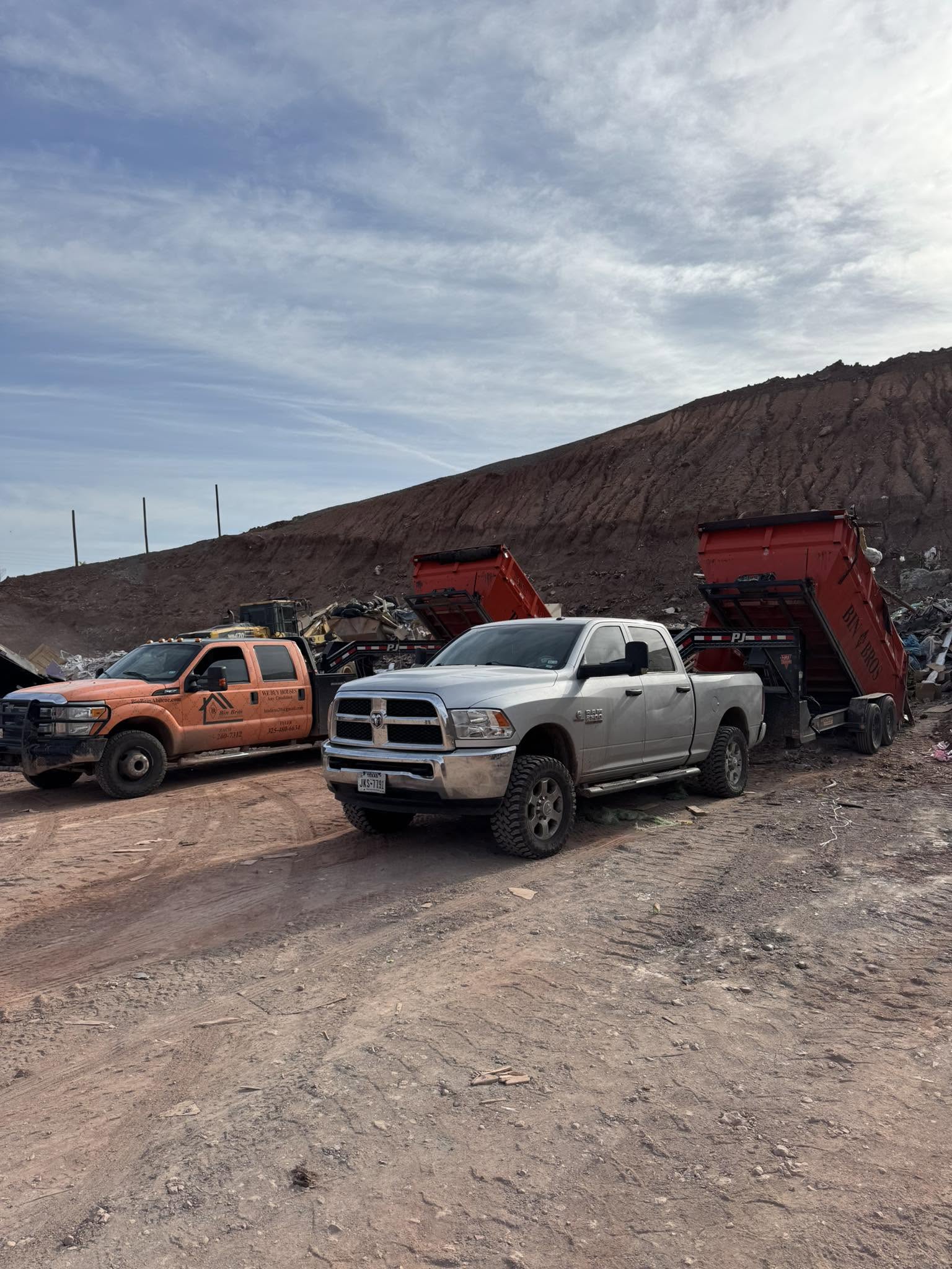 Bin Bros trucks and raised roll-off containers at a debris site